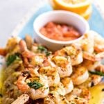 Grilled shrimp kabobs on platter with shrimp sauce. With Pinterest overlay.