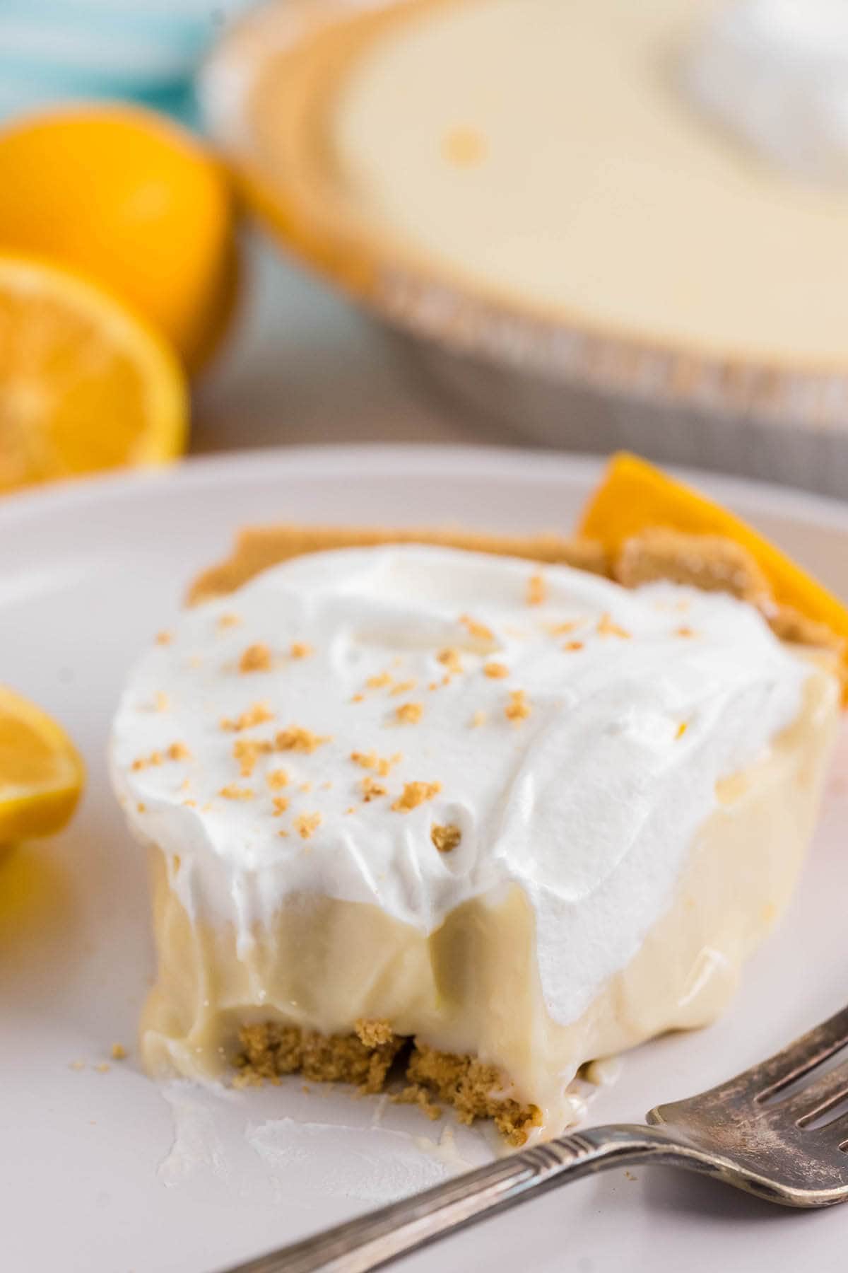 A close up photo of a slice of lemon icebox pie with bite taken out of it.