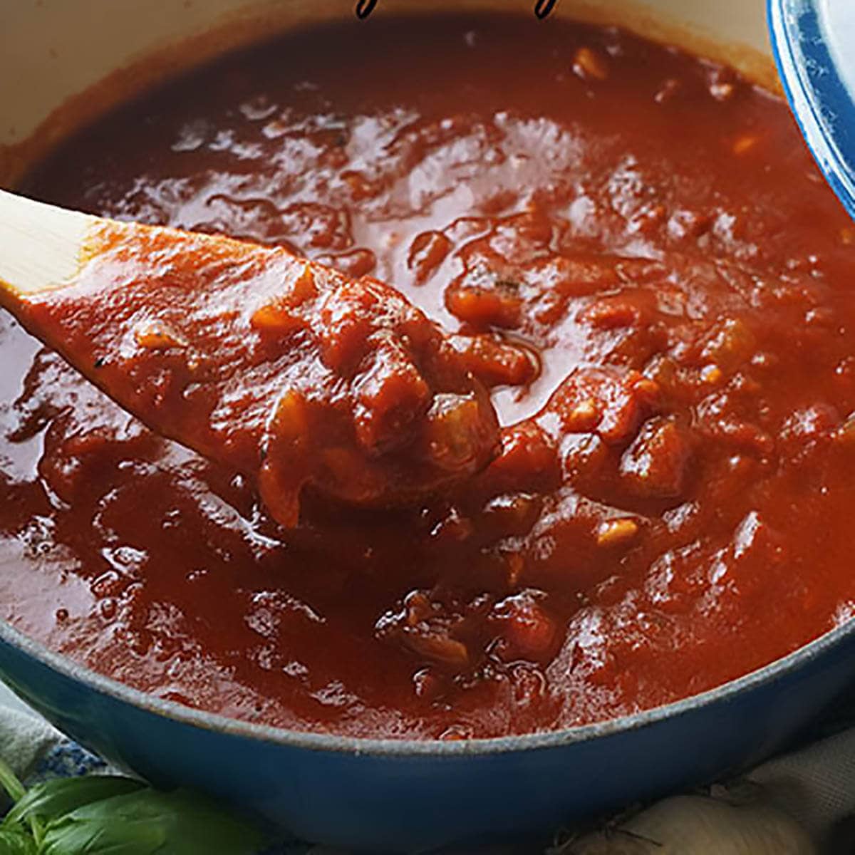 A big pot filled with marinara sauce with serving spoon.