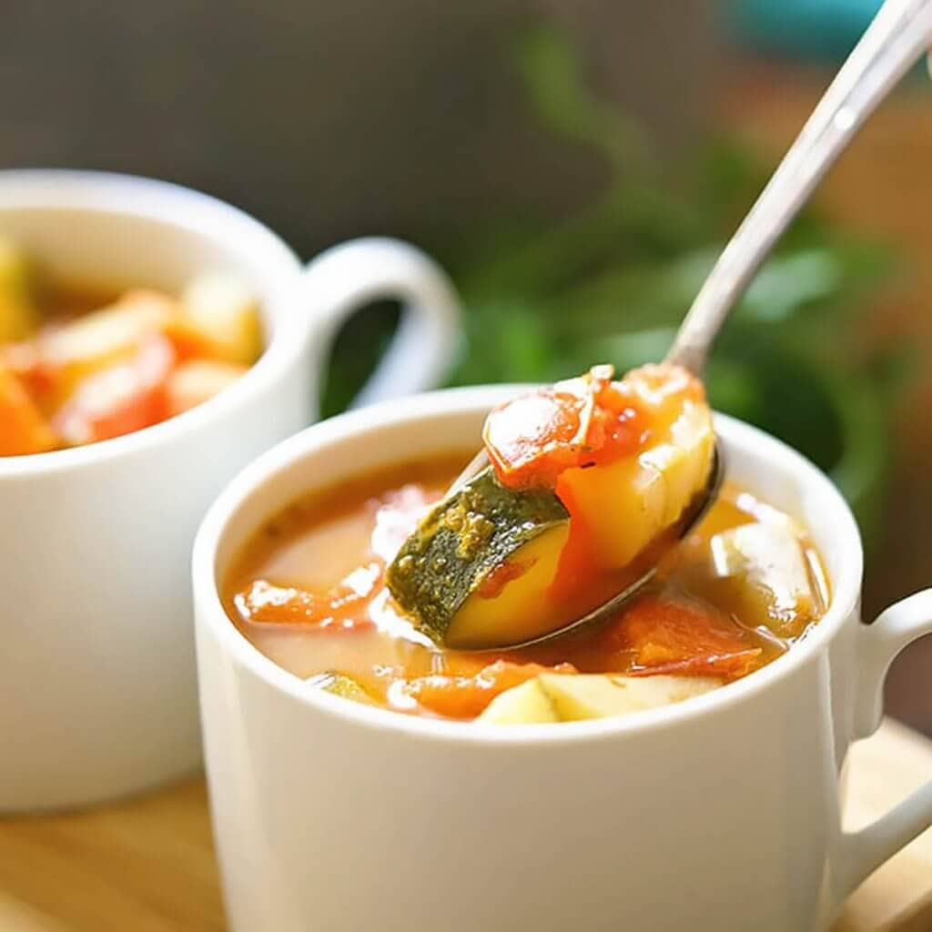 Two bowls of roasted tomato soup in bowls with spoon.