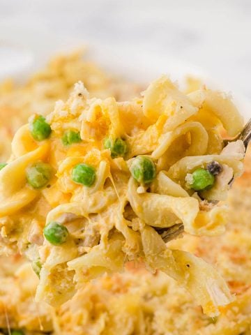 Noodle Casserole with peas on spoon.