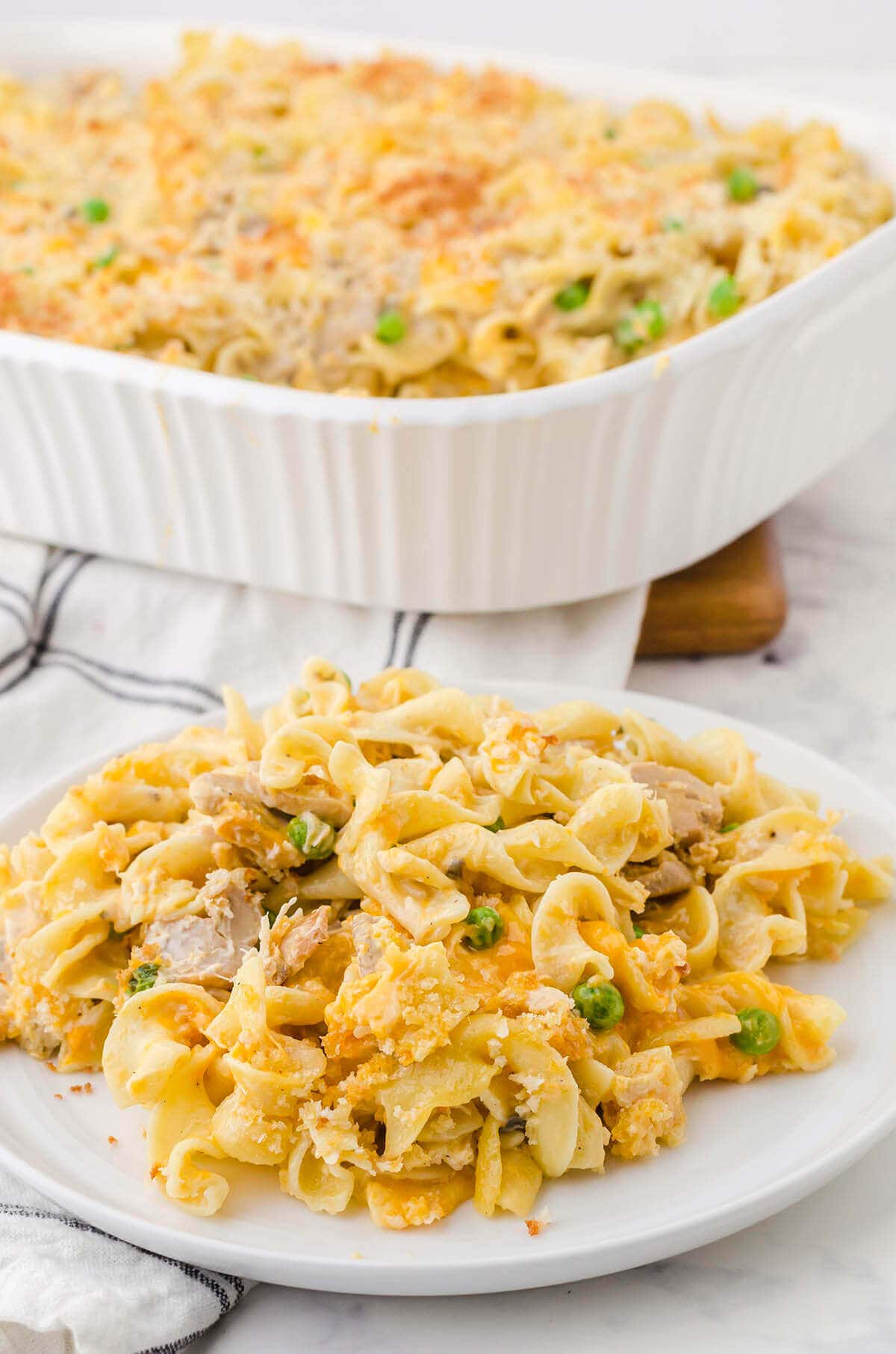 Plate filled with tuna noodle casserole, with full casserole dish in the background.