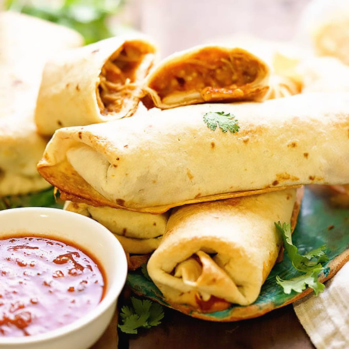 A plate filled with chicken chimichangas with a side of dipping sauce. 