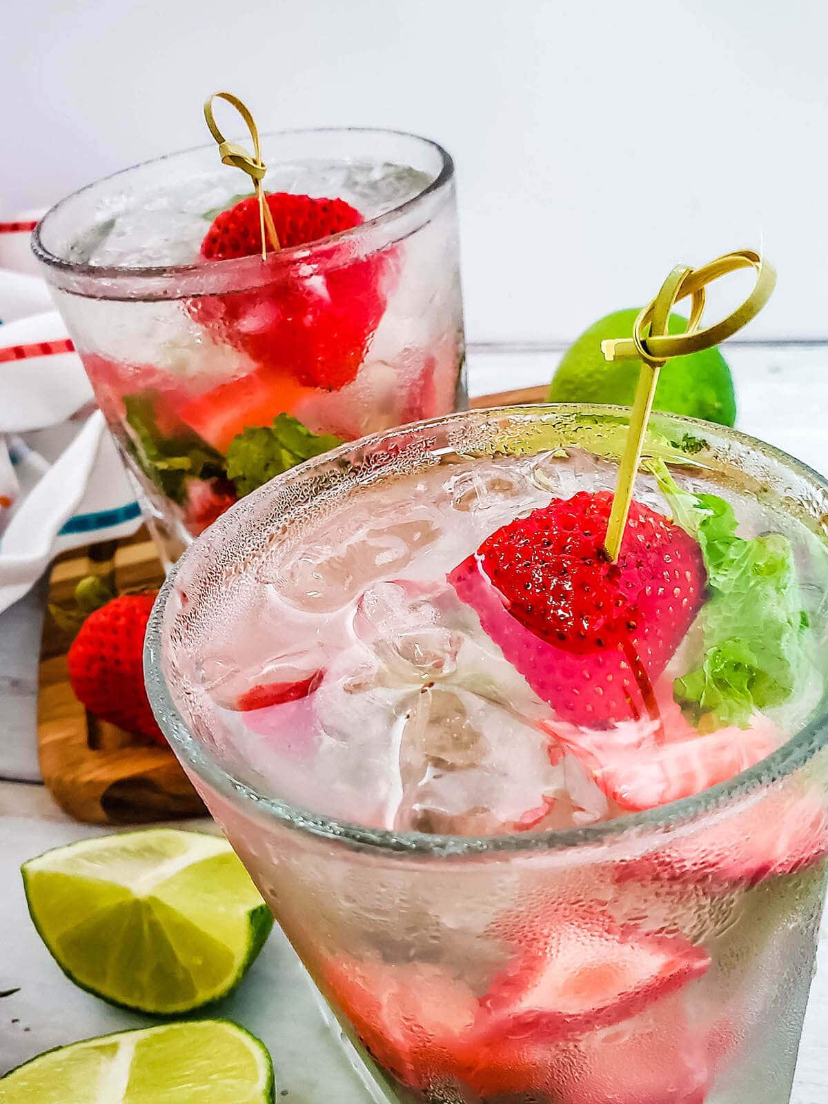 Two festive cocktails garnished with fruit.