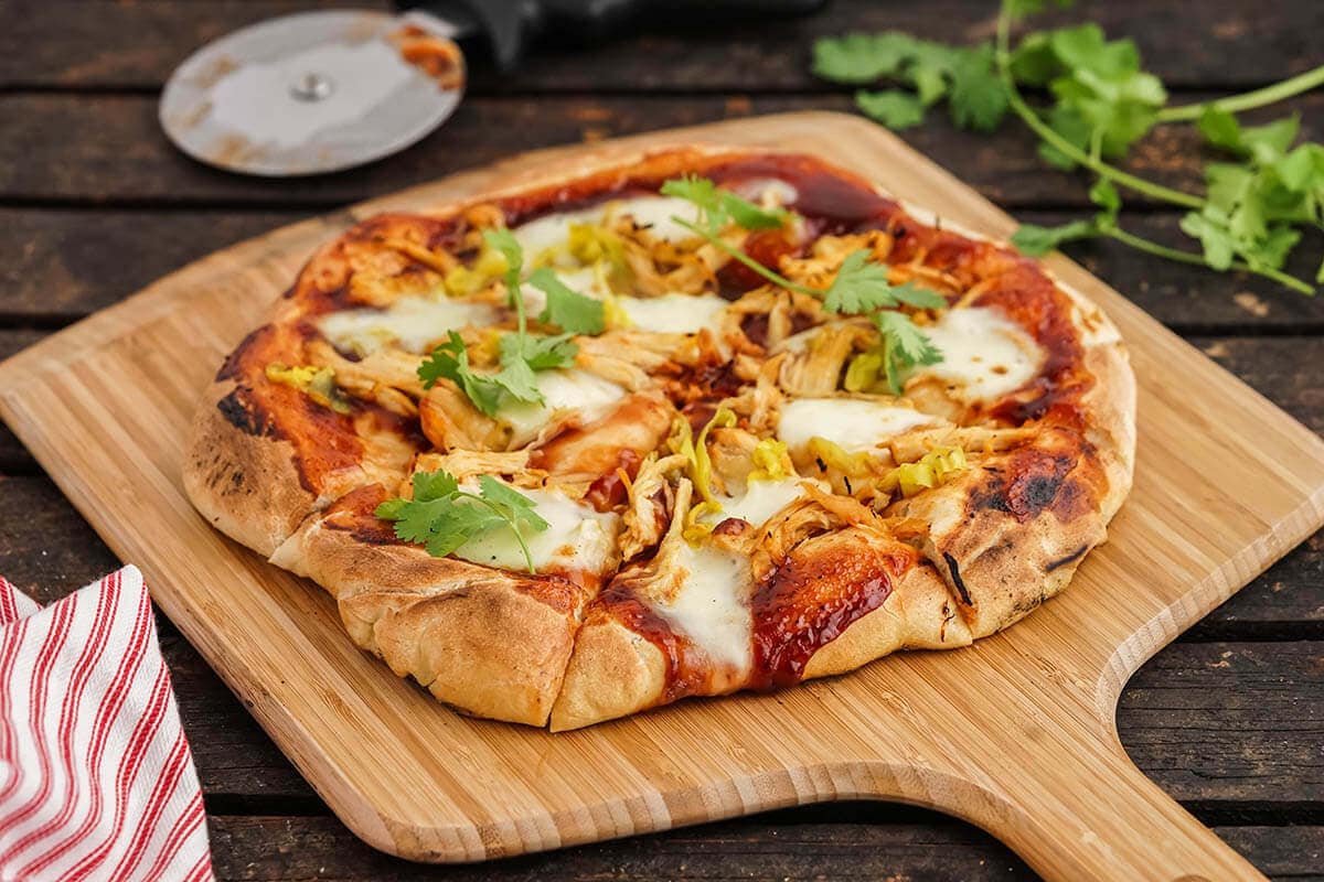 CPK BBQ Chicken Pizza Recipe on pizza peel topped with sprigs of cilantro.