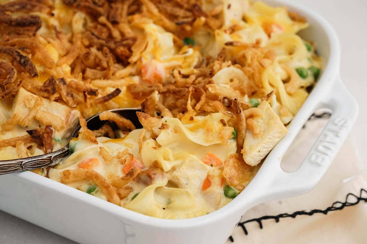 Chicken and Egg Noodle Casserole in white casserole dish with serving spoon.
