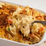 Chicken Noodle Casserole in pan with spoon scooping a serving.