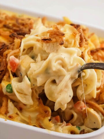 Chicken Noodle Casserole in pan with spoon scooping a serving.