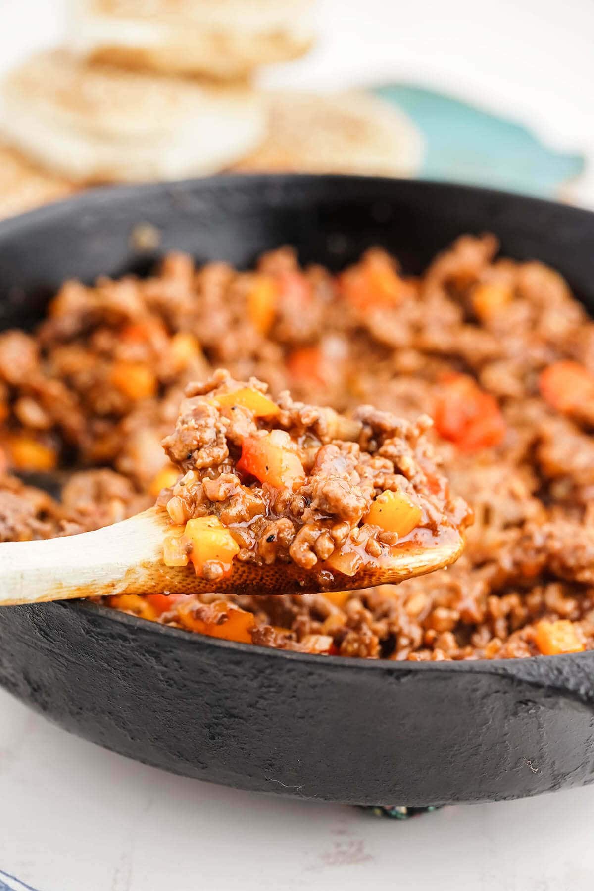 Cast iron skillet filled with old fashioned sloppy joes recipe, with serving spoon.