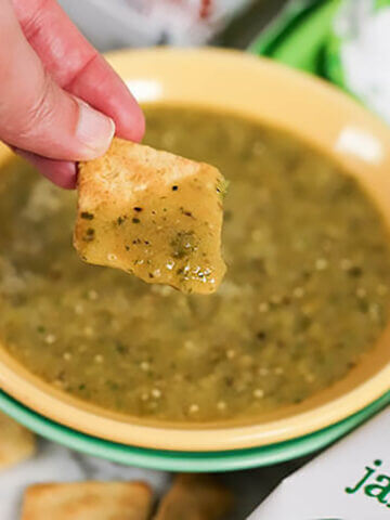 Salsa Verde in bowl with hand dipping chip.