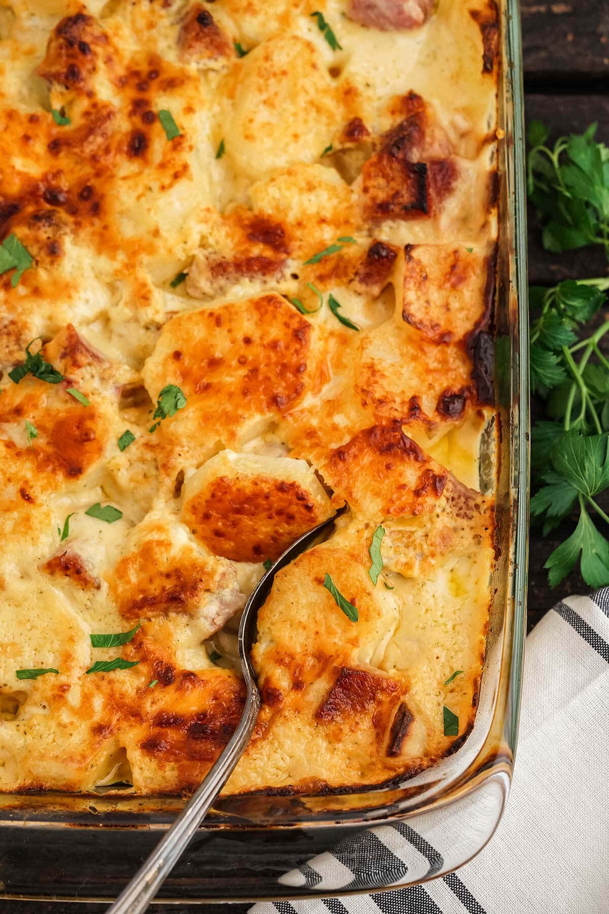 Baked ham and potato casserole with serving spoon.
