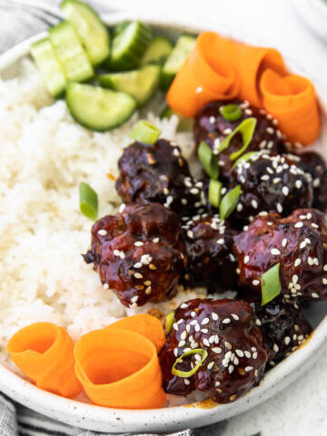 Asian Meatball bowl served with white rice, shredded carrots and cucumbers.