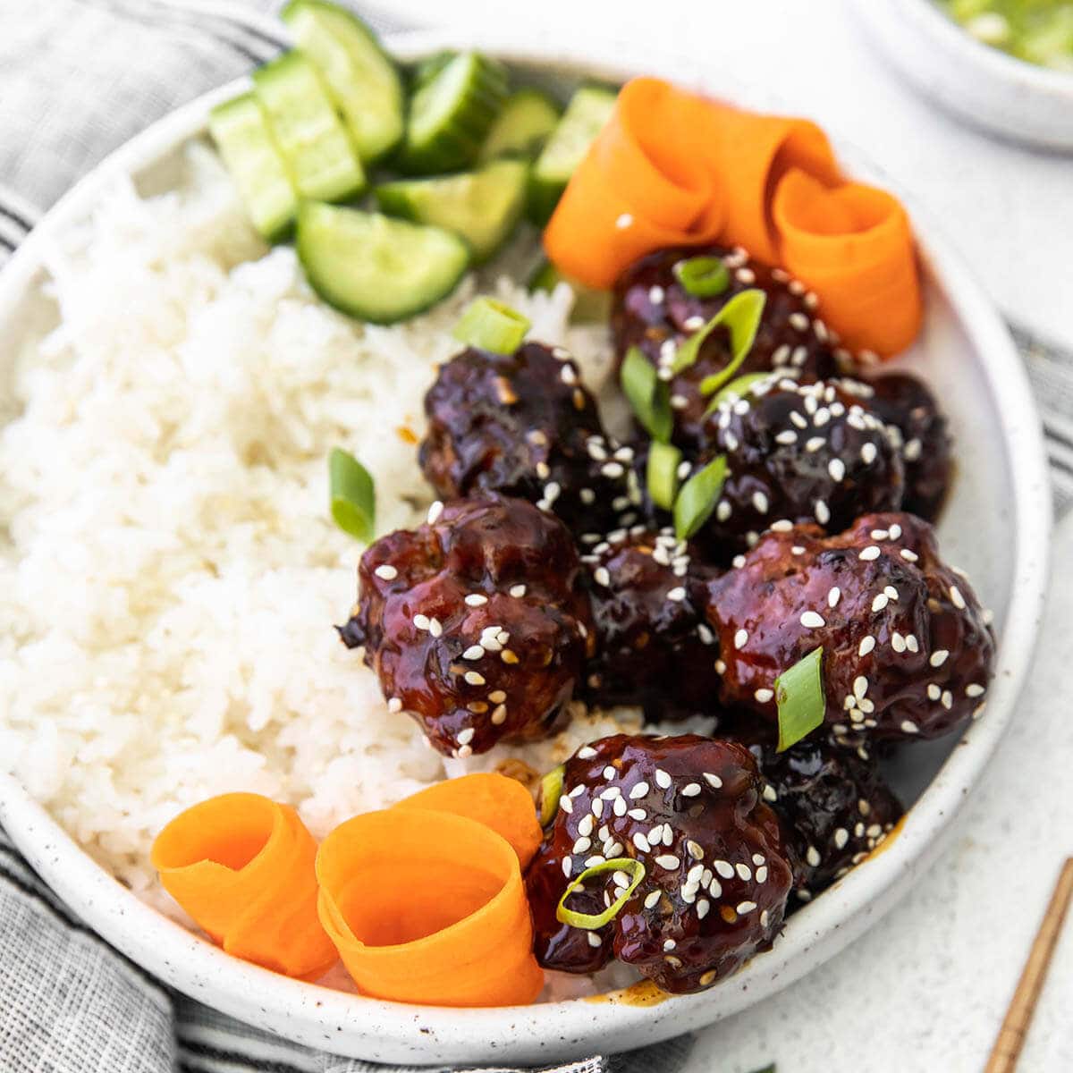 Asian Meatball bowl served with white rice, shredded carrots and cucumbers. 