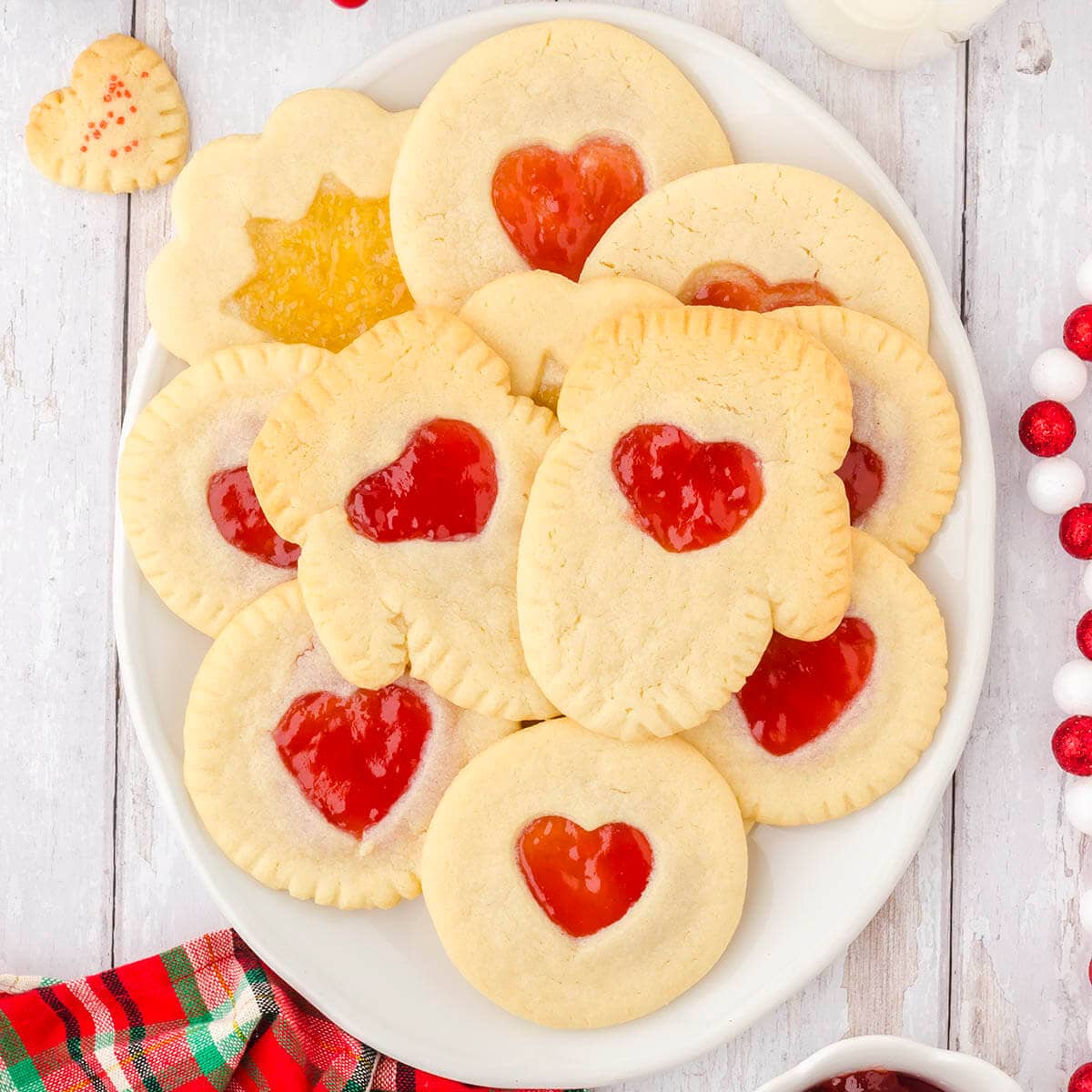 Sugar Cookies with cut out with strawberry center on white platter.