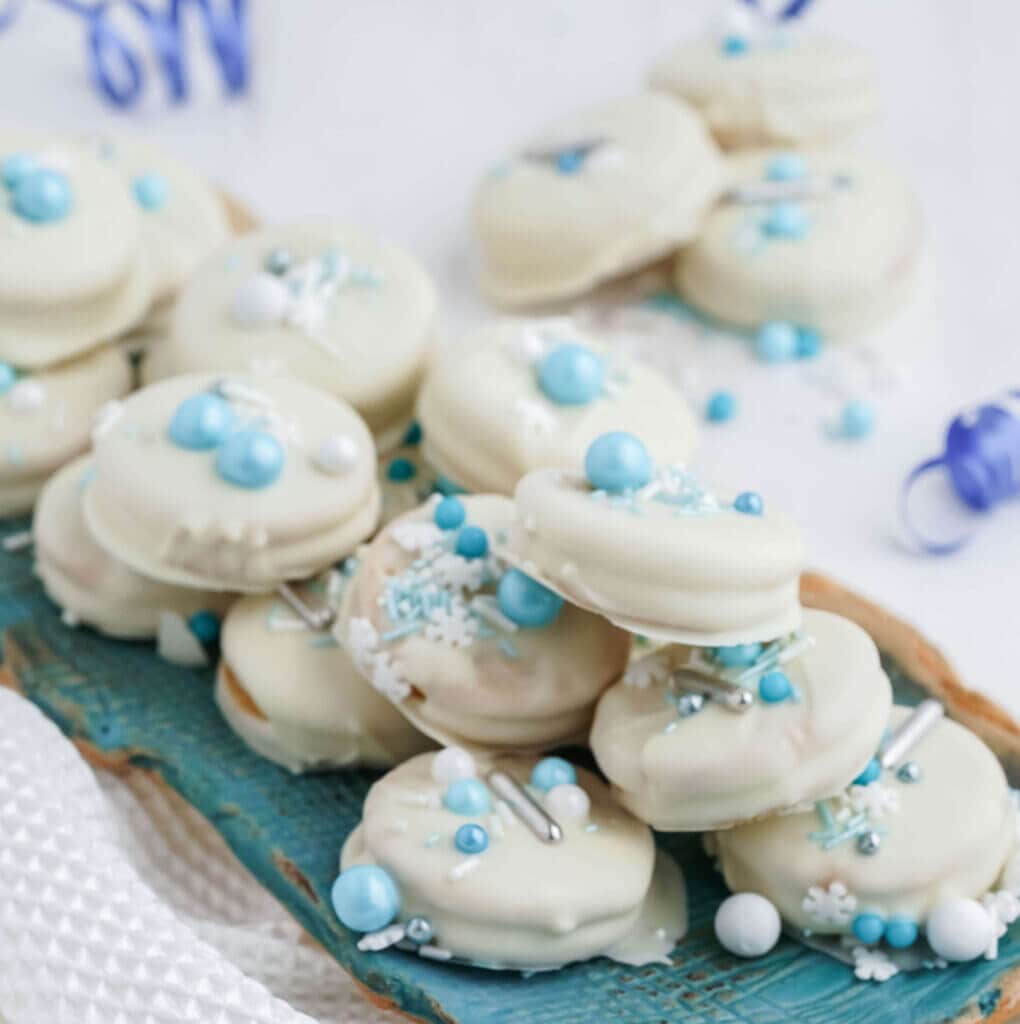 A blue platter stacked with white chocolate dipped cookies.