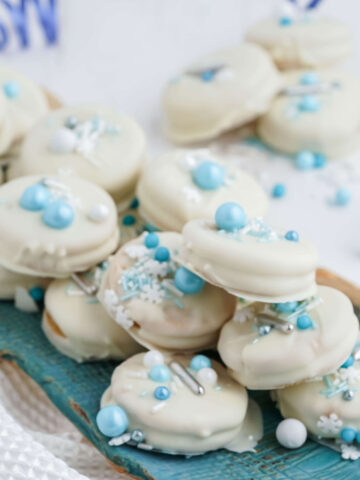 A blue platter stacked with white chocolate dipped cookies.