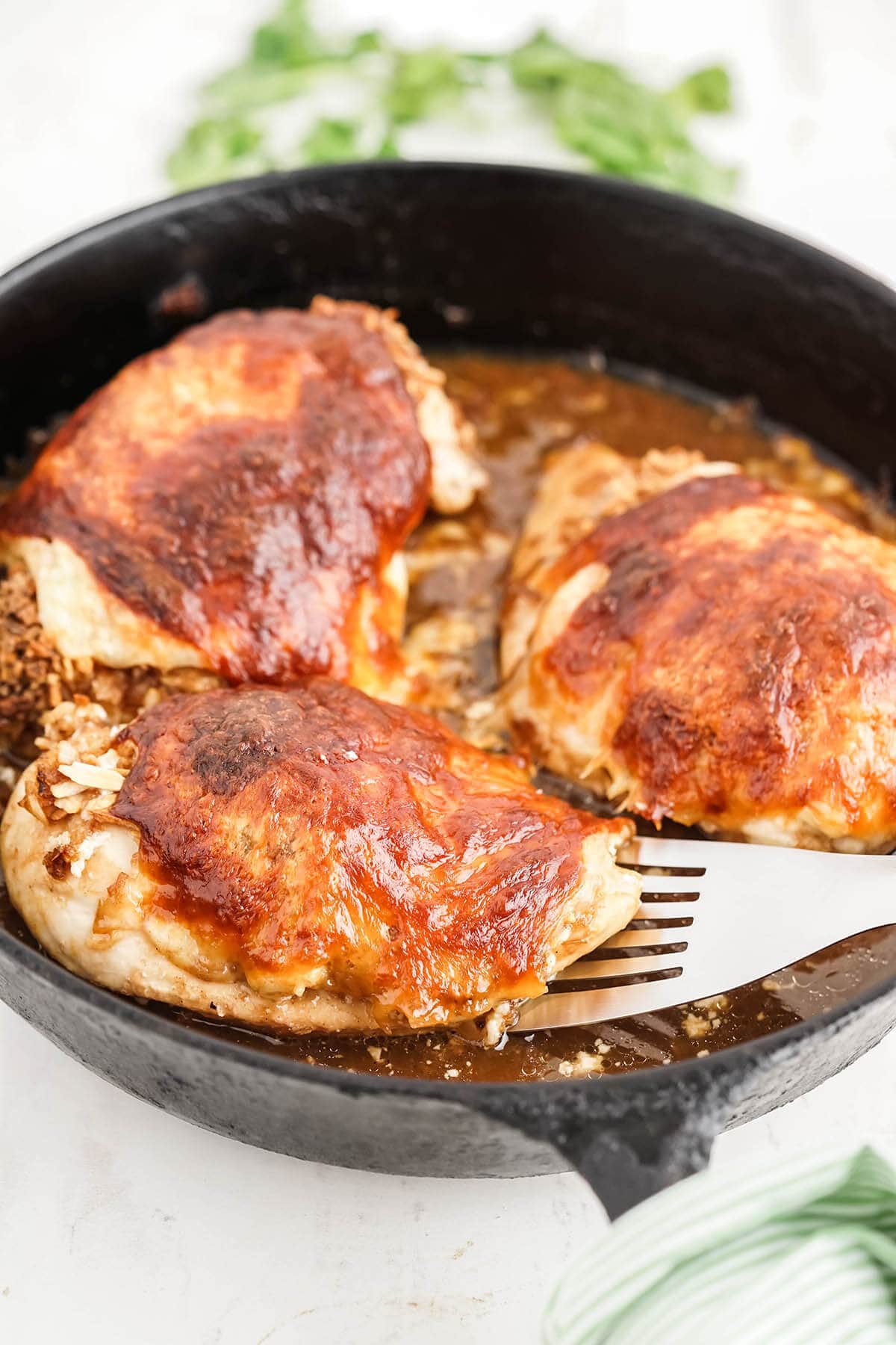 Baked French Onion Chicken in cast iron pan with serving spatula.