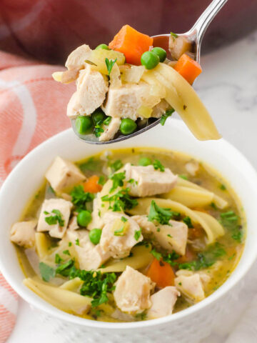 Chicken noodle soup in bowl with serving spoon.
