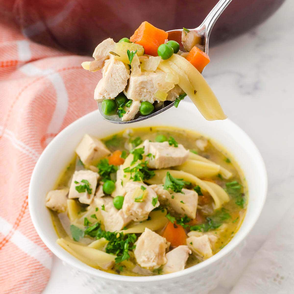 Chicken noodle soup in bowl with serving spoon.