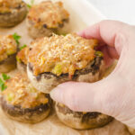 Baked Italian stuffed mushroom with hand holding one that's ready to eat!