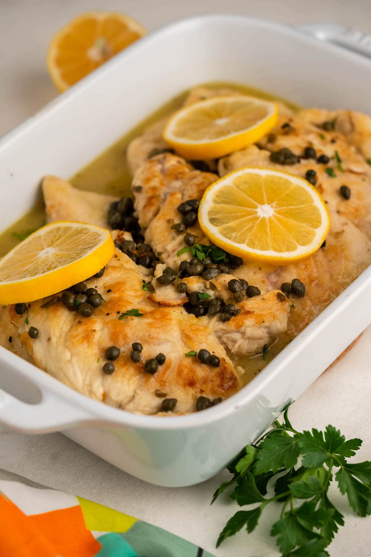 CPK Chicken Piccata in casserole dish garnished with lemons.