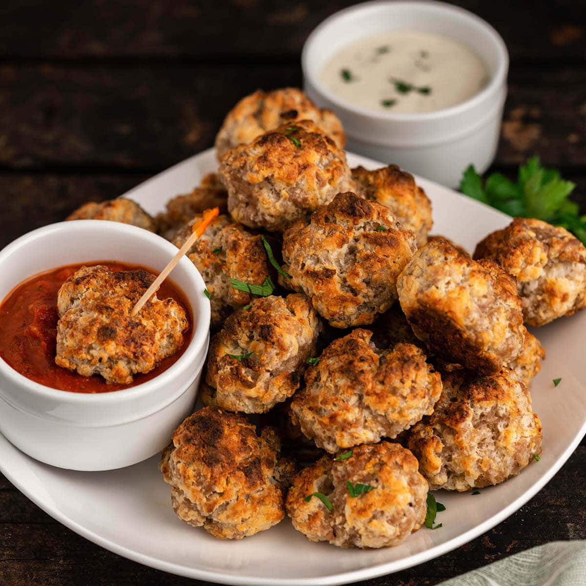 Sausage balls on platter with marinara and ranch dip.