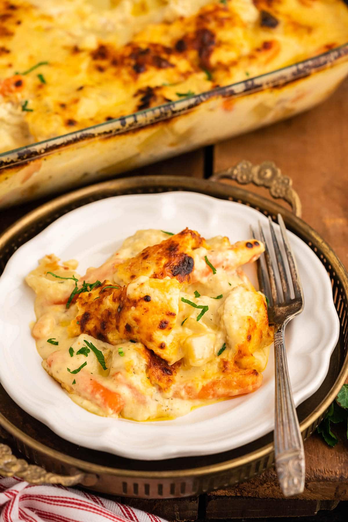 Chicken and Potato Bake on plate with fork and casserole dish. 