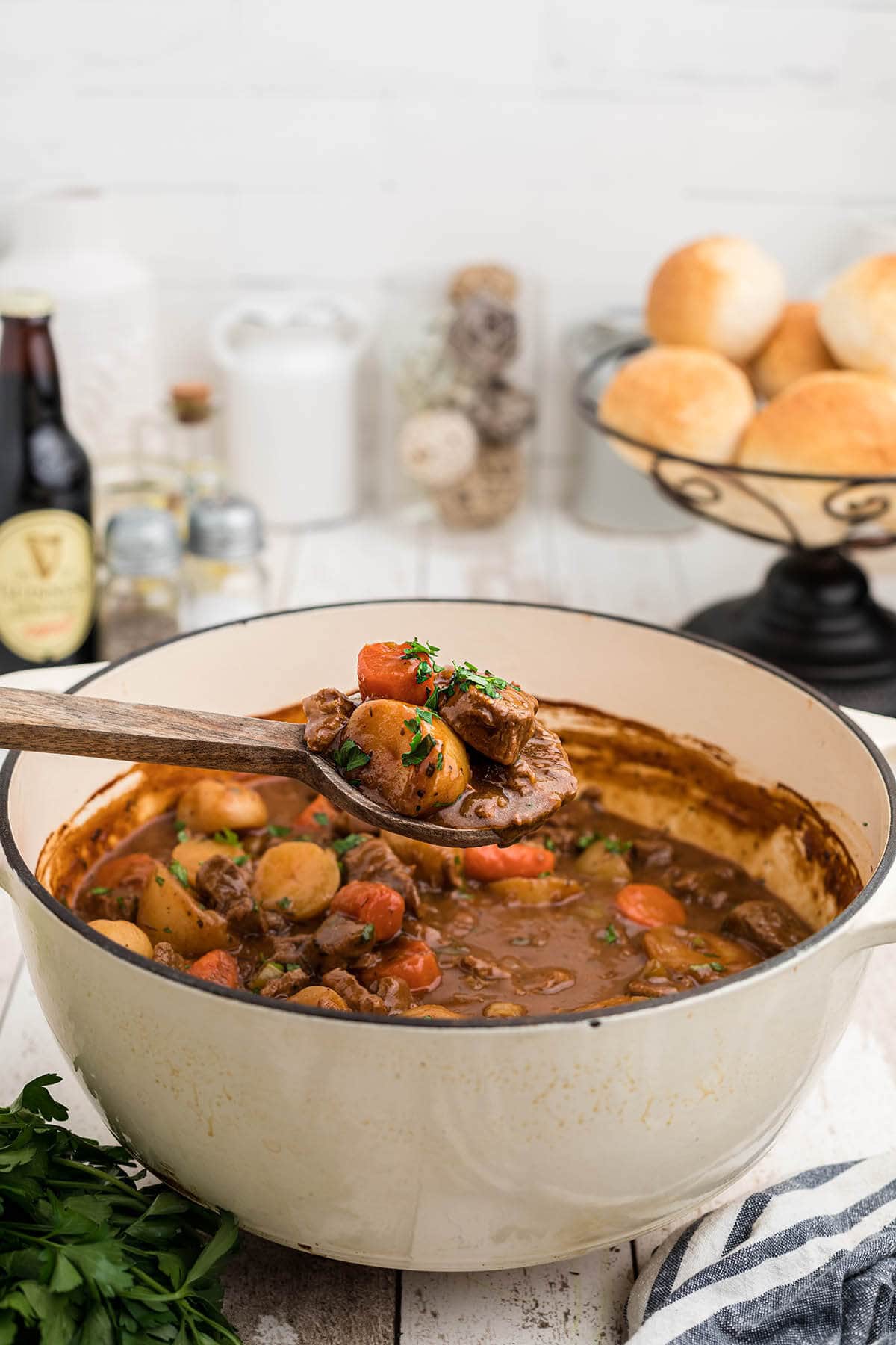 White pot filled with Guinness beef stew recipe with ladle dishing up soup. 