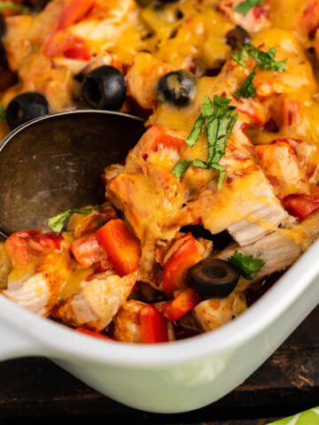Chicken Enchilada Casserole in baking dish with serving spoon.