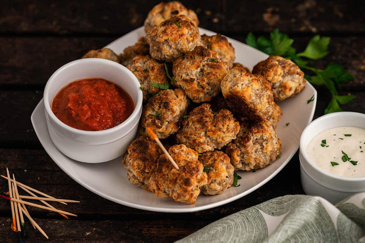 Sausage Ball Recipe with Cream Cheese on platter with dipping sauce.
