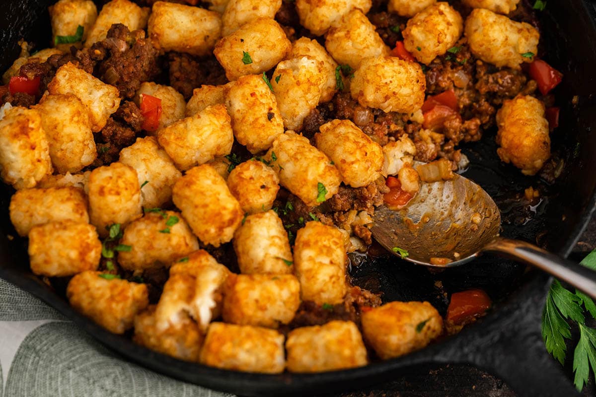 Skillet casserole topped with tater tots. With serving spoon.