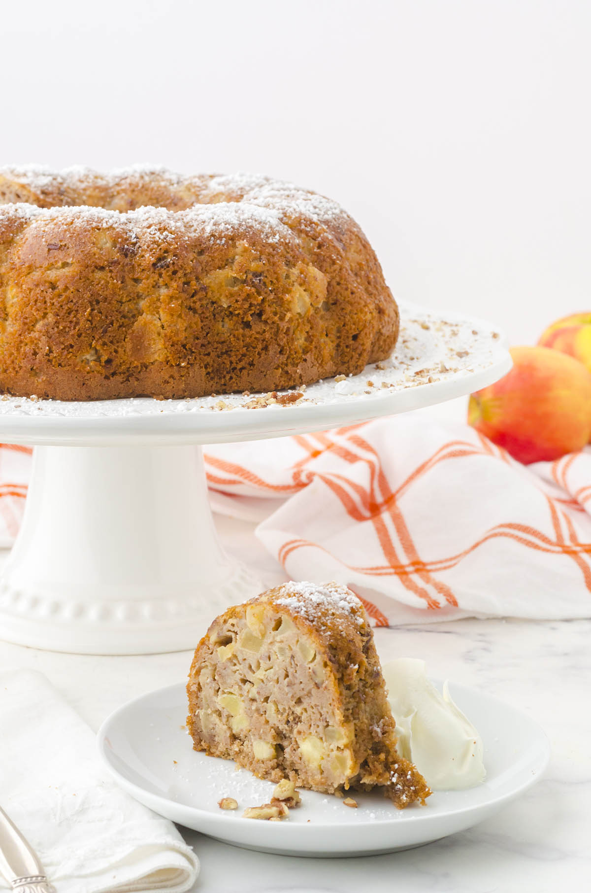 Apple Bundt Cake on cake stand with a slice of cake on a plate. 