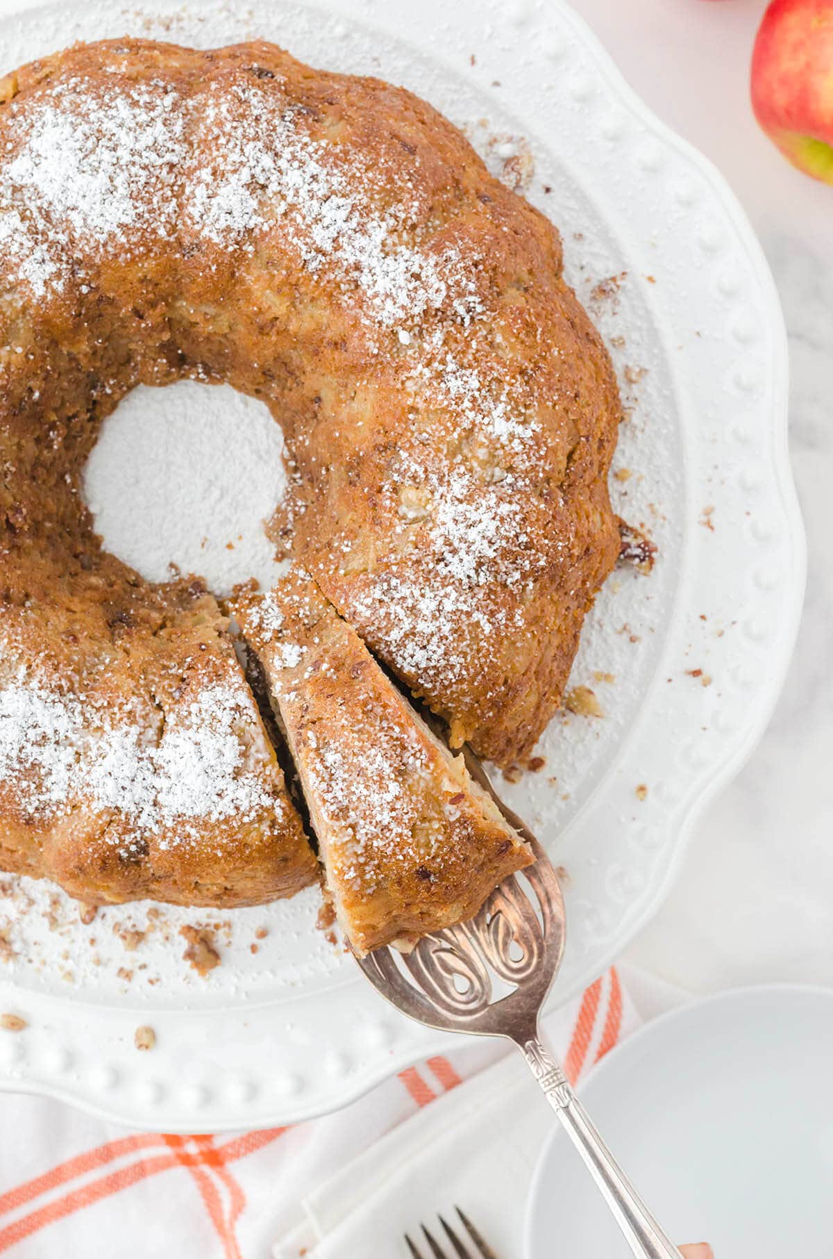  Overhead photo of bundt cake on cake stand with slice on serving knife. 