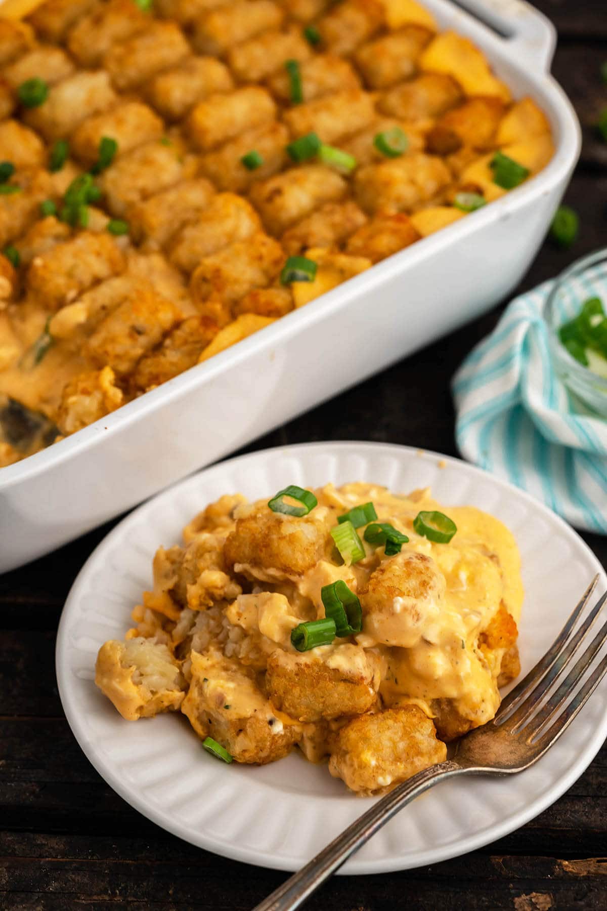 Plate filled with tater tot casserole with casserole dish off to the side. 