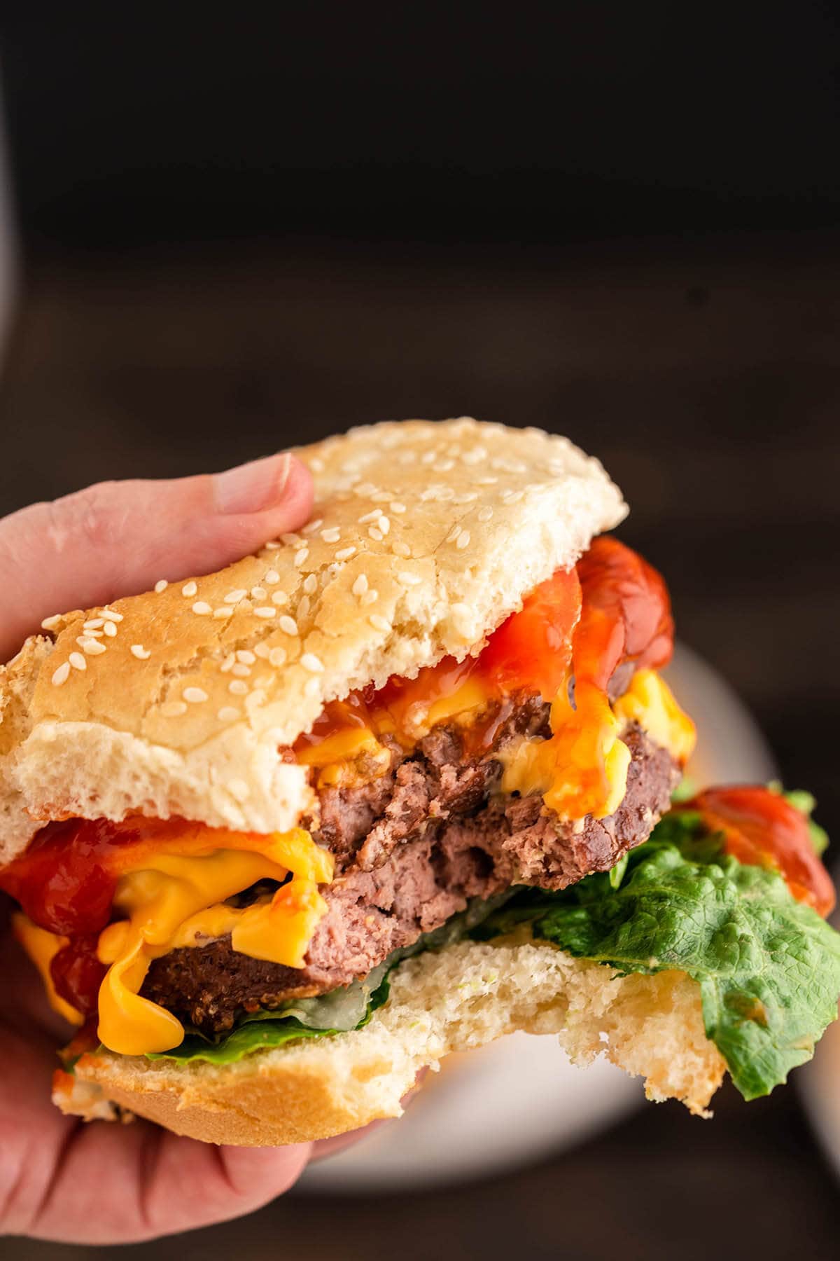 How to Cook Frozen Hamburger Patties in the Oven, loaded burger with bite taken out.