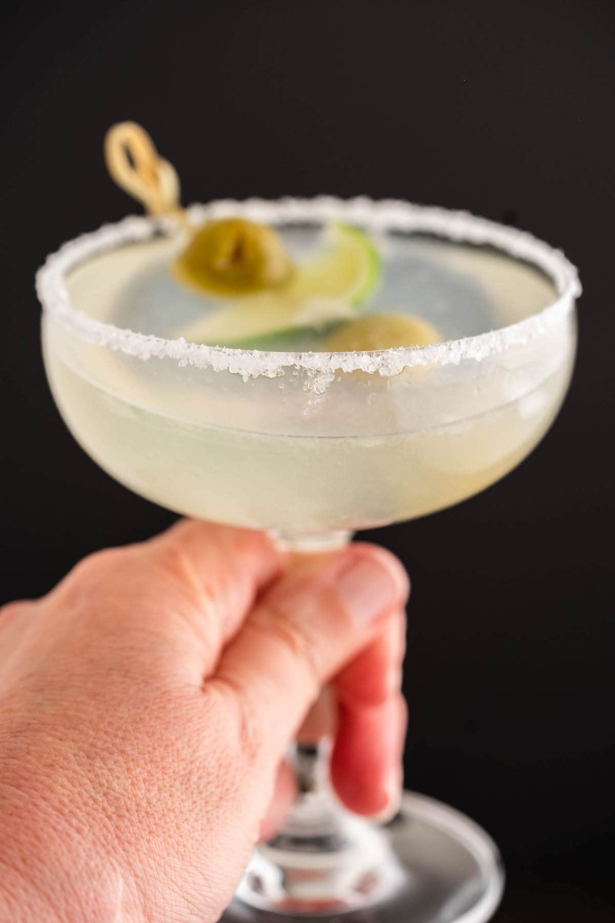 Mexican Martini Recipe in glass garnished with olives and lime.