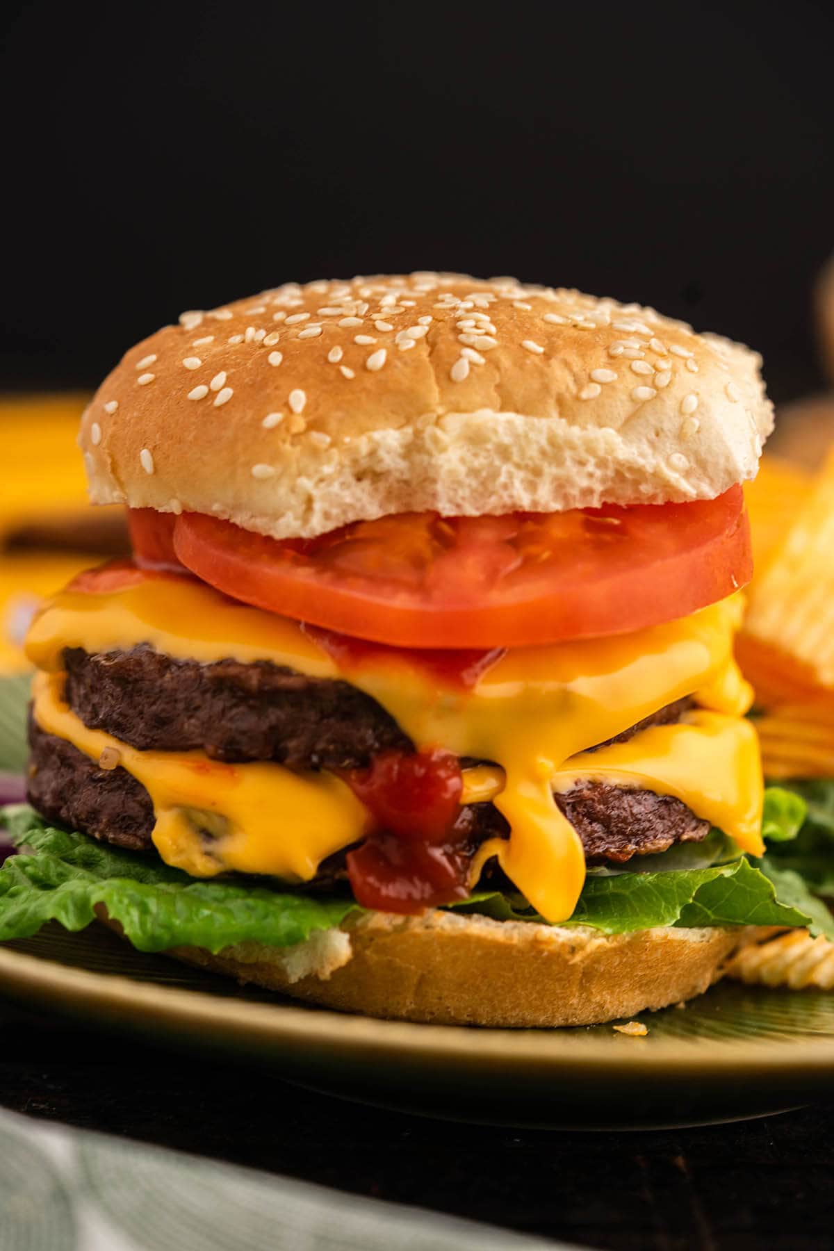 Loaded Cheeseburger on plate with pickles on the side.