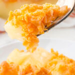 Fruit casserole in baking dish with serving spoon. With Pinterest overlay.