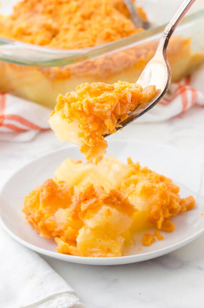 Pineapple casserole on a plate with a fork holding a bite of the casserole.