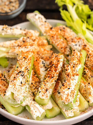 Celery stuffed with cream cheese topped with everything bagel mix on platter.