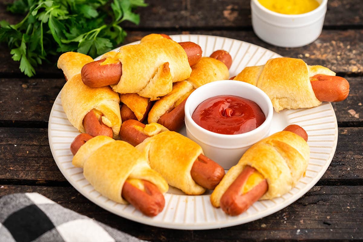 Chese Stuffed Crescent Roll Hot Dogs on platter served with catsup and mustard. 