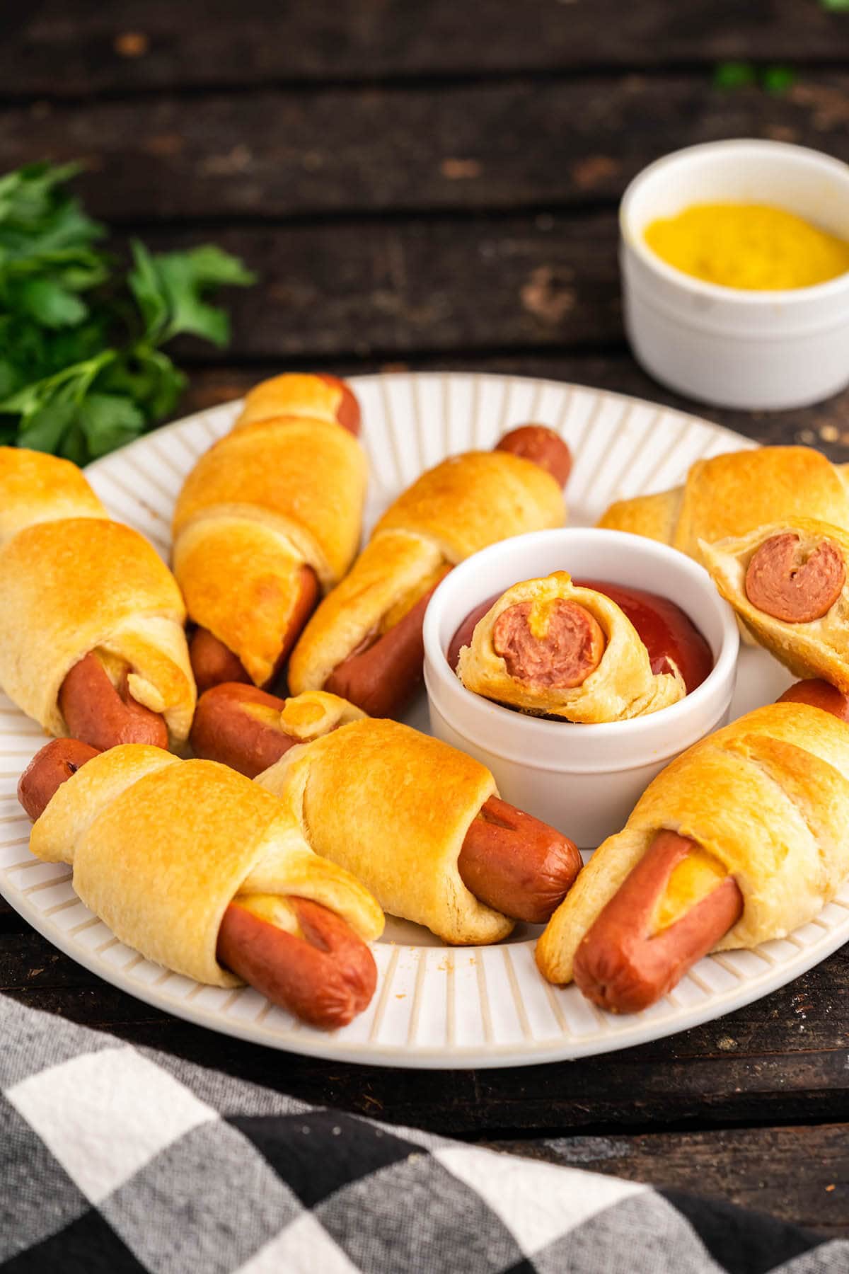 Baked cheese Stuffed Crescent Roll Hot Dog Recipe piled on platter served with catsup and mustard. 