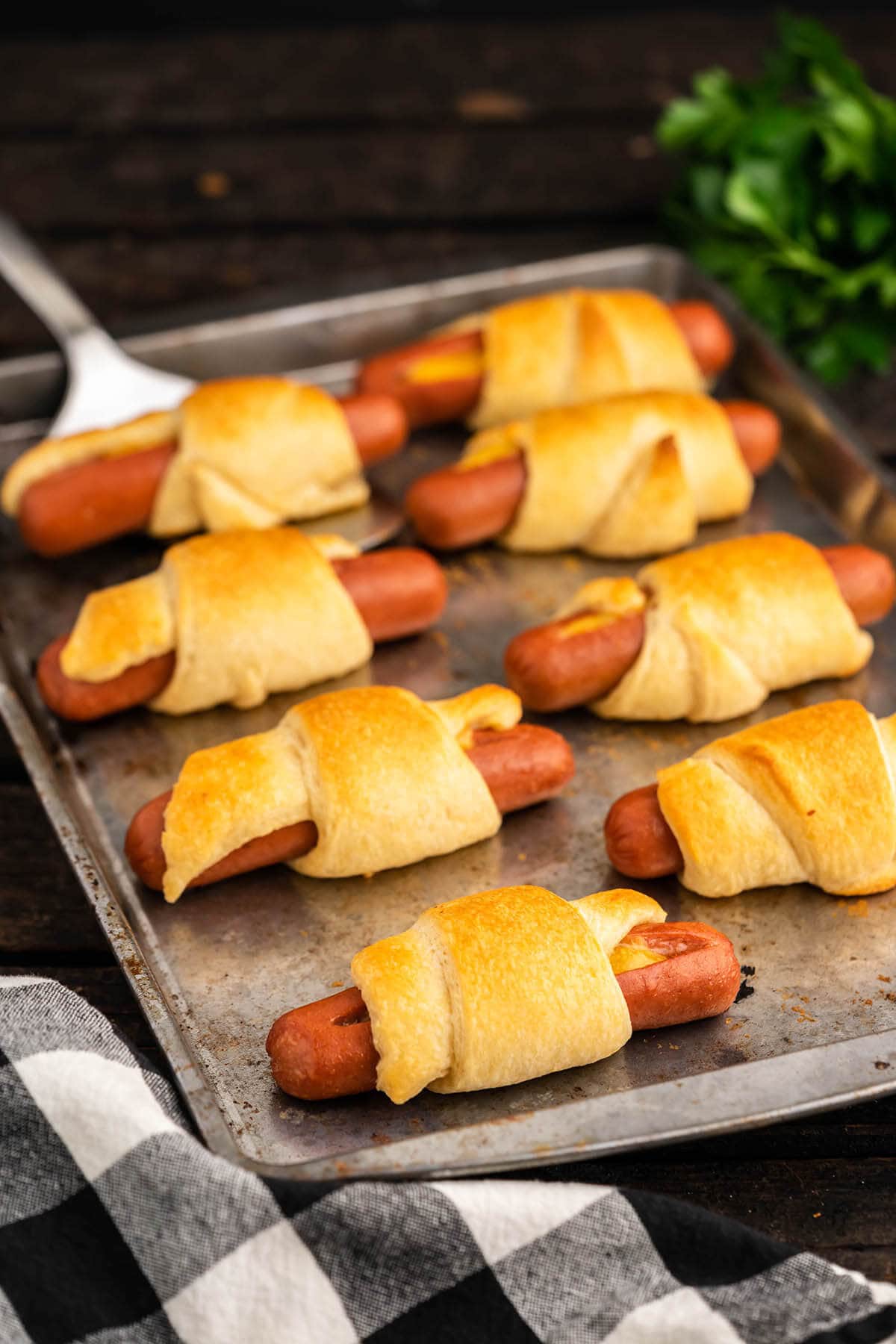 Pigs in a blanket on baking sheet with serving spatula. 
