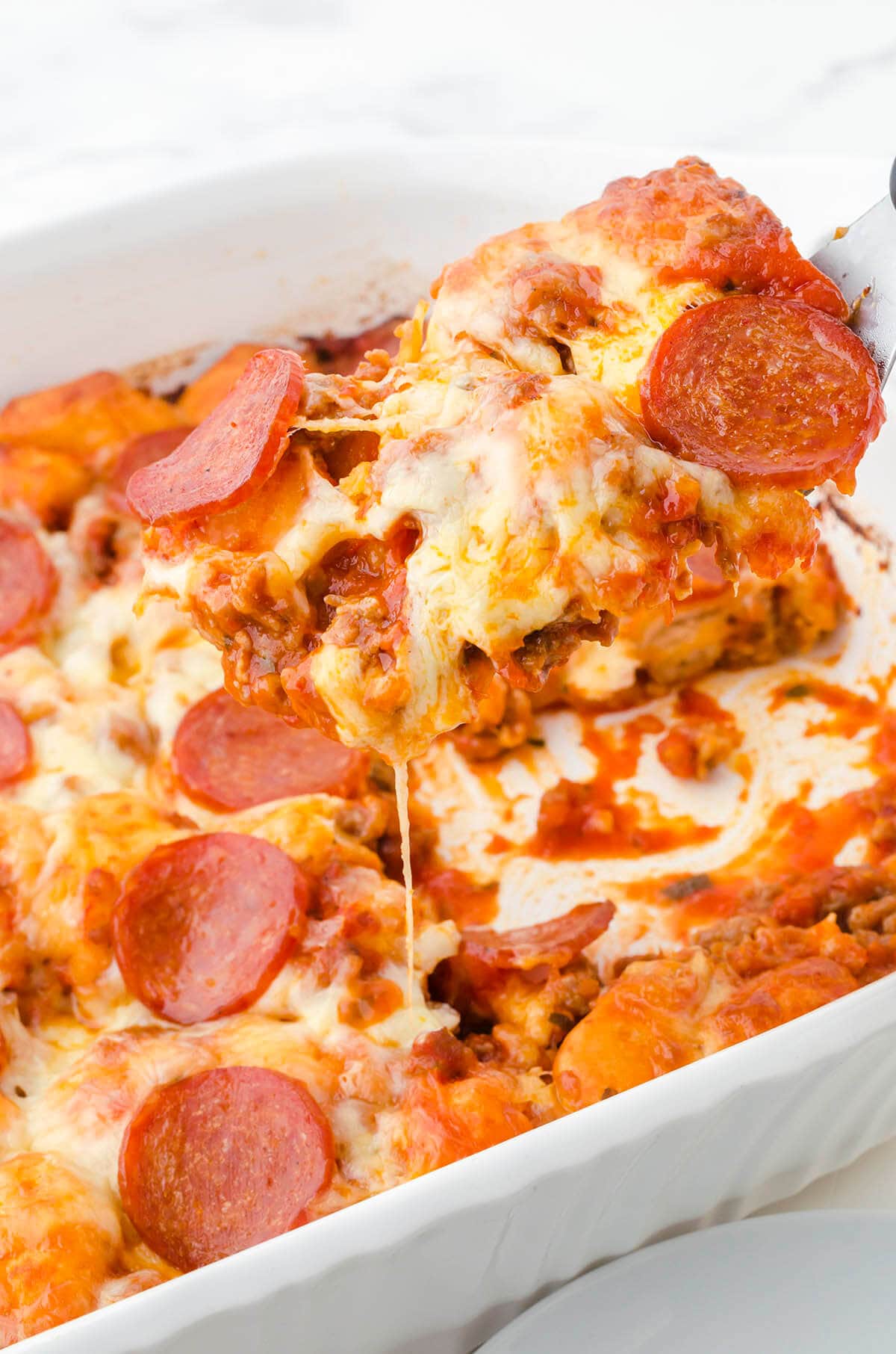 Pizza Casserole in baking with serving spatula. 