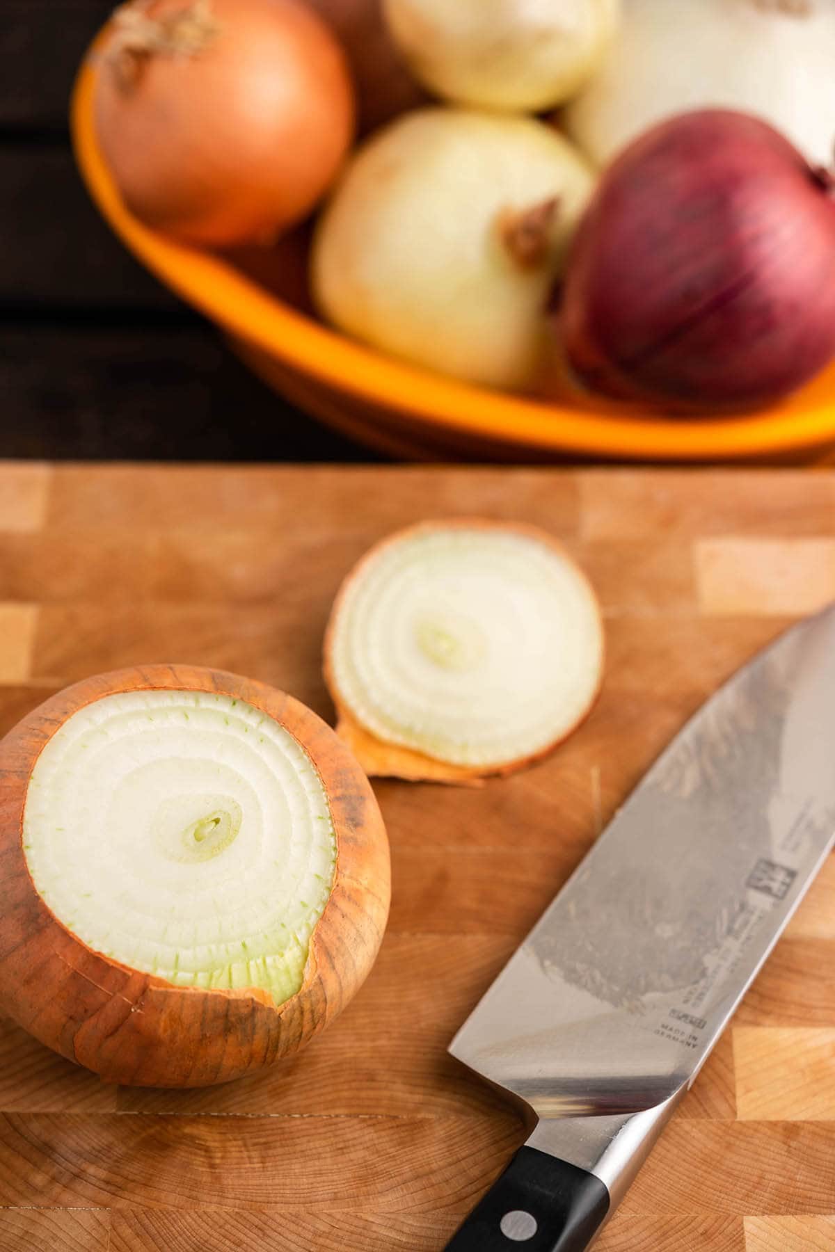 Yellow onion on cutting board with stem removed.