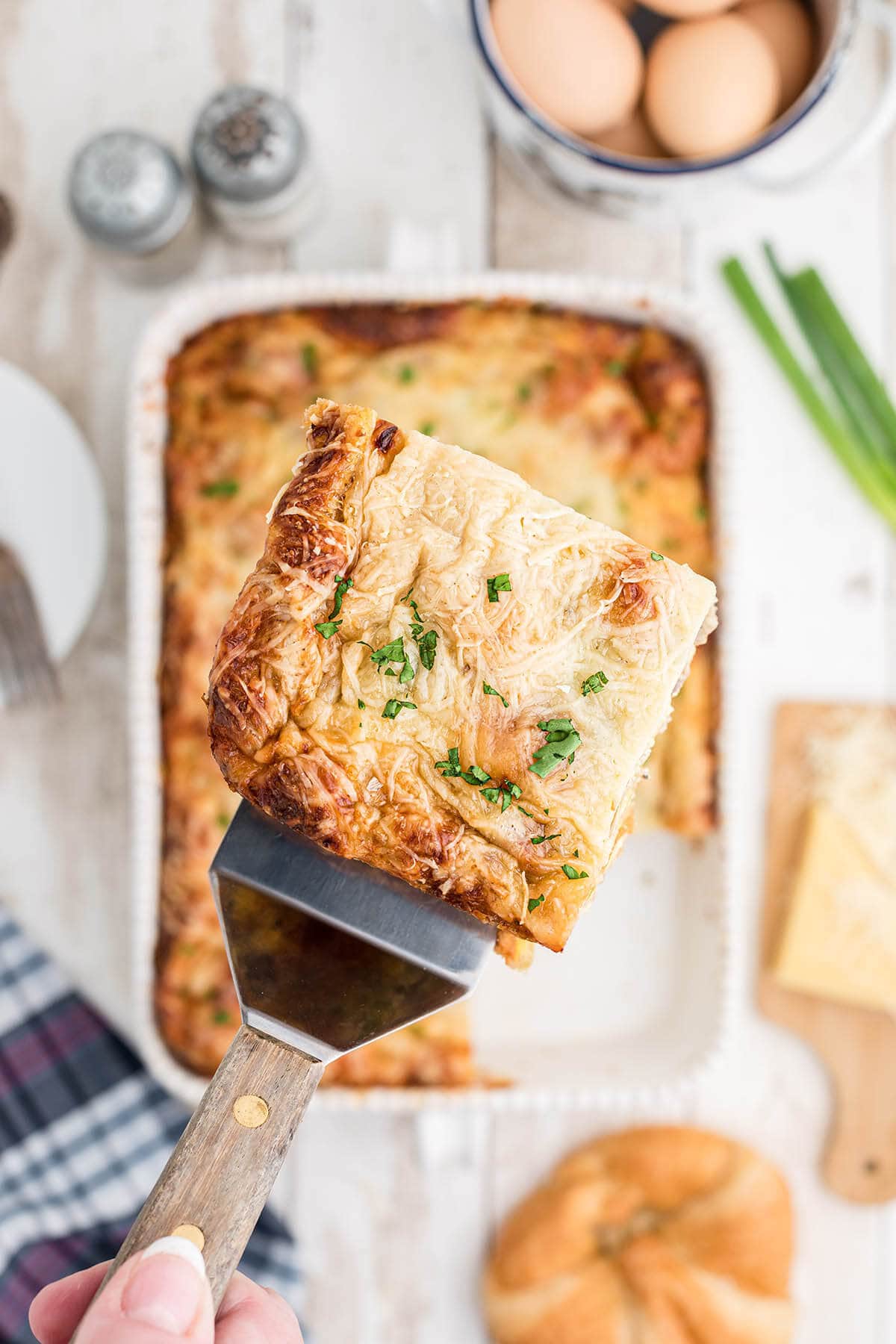 Sausage Crescent Roll Breakfast Casserole in baking dish with spatula dishing up a serving. 