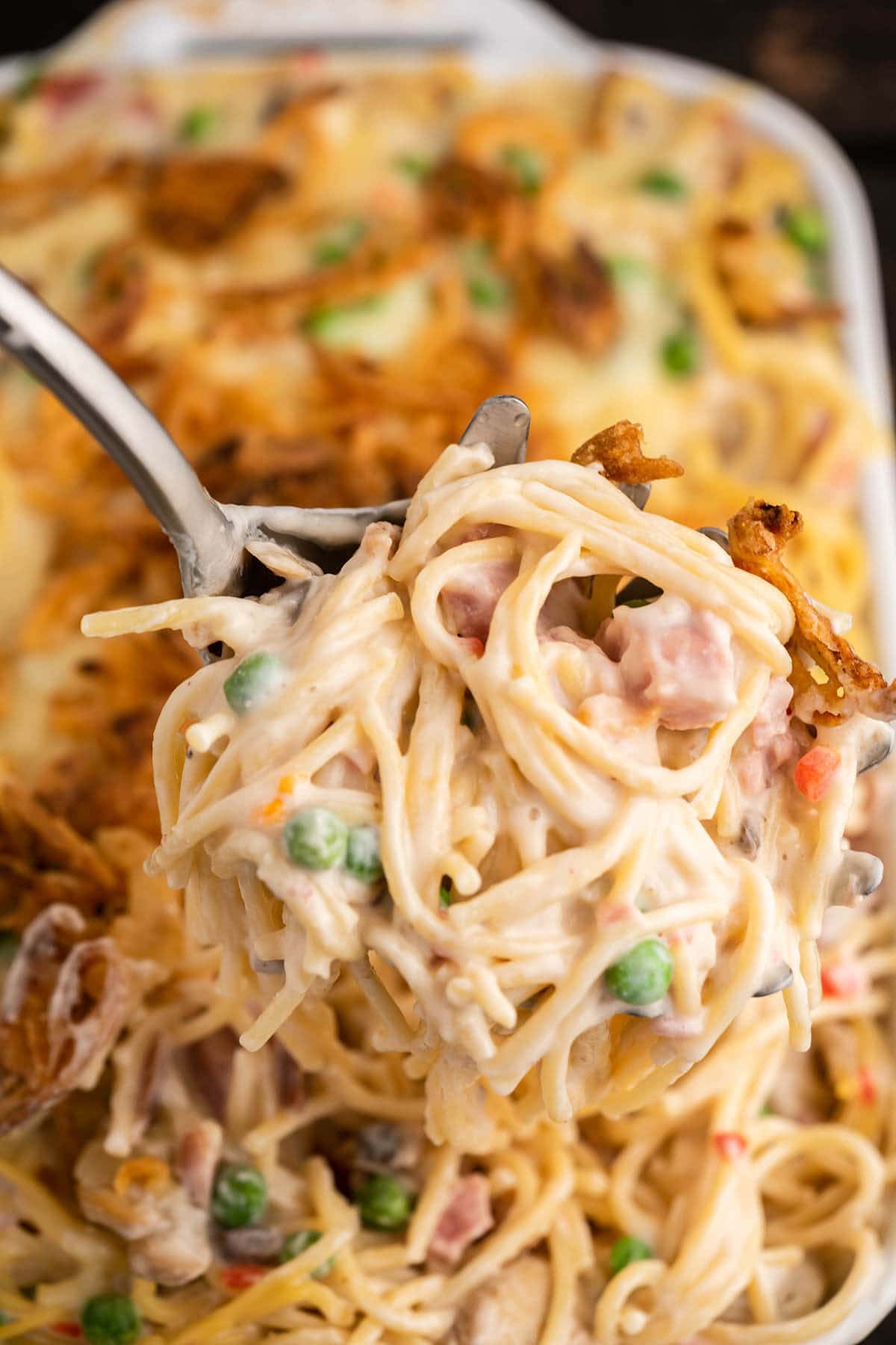 Cheesy pasta in casserole dish with serving spoon.