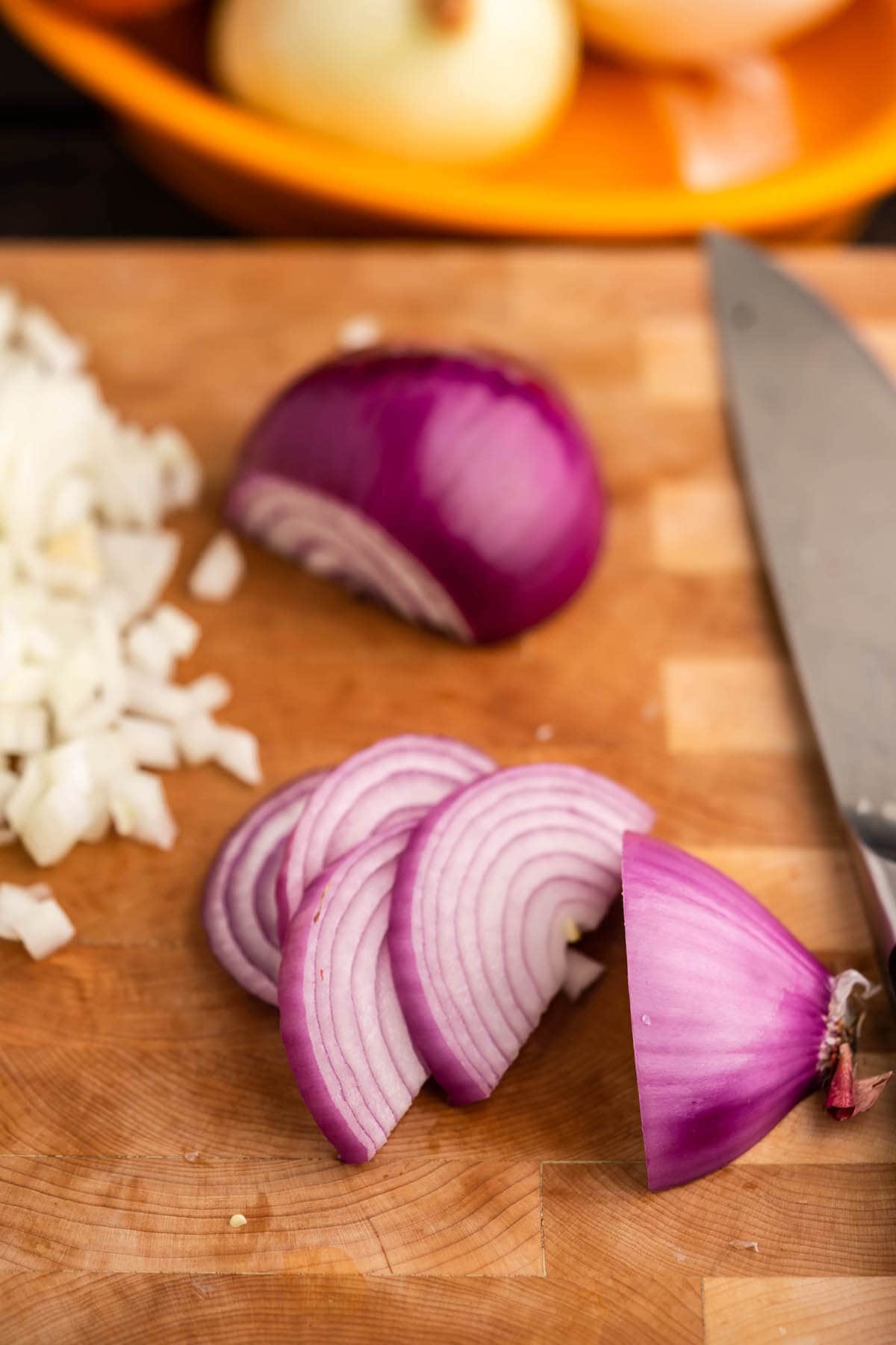 Red onion sliced on cutting board with knife. 