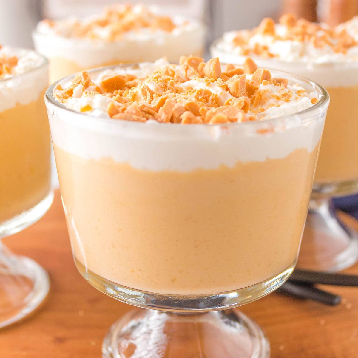 Butterscotch pudding desserts in serving cups topped with whipped cream and butterscotch chips. 