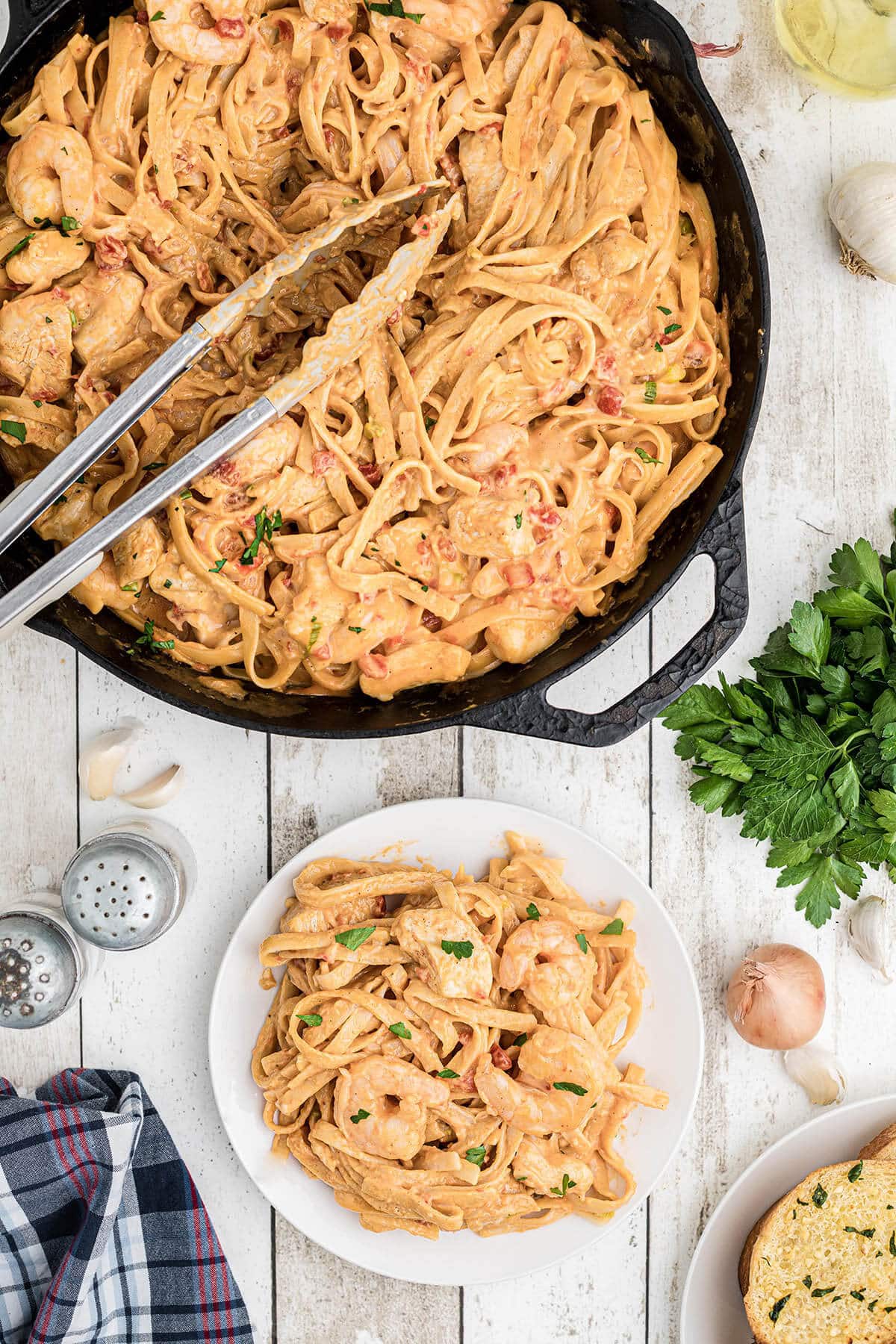 Cheesy pasta in a skillet with serving tongs.